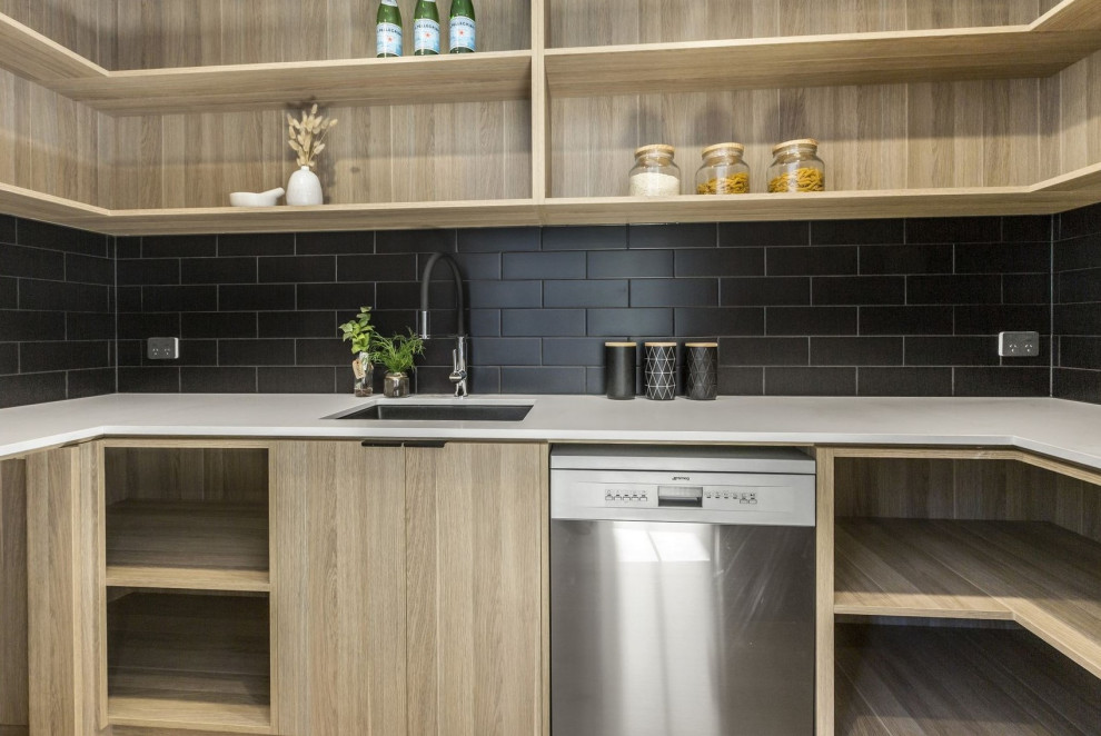 Photo of a large modern galley open plan kitchen in Melbourne with a submerged sink, flat-panel cabinets, light wood cabinets, engineered stone countertops, black splashback, porcelain splashback, stainless steel appliances, light hardwood flooring, an island, brown floors and white worktops.
