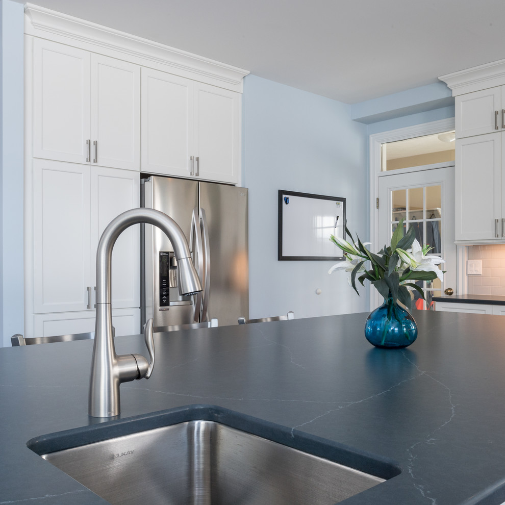 Klassisk inredning av ett stort blå blått kök, med en undermonterad diskho, skåp i shakerstil, vita skåp, bänkskiva i kvarts, vitt stänkskydd, stänkskydd i keramik, rostfria vitvaror, mellanmörkt trägolv, en köksö och brunt golv
