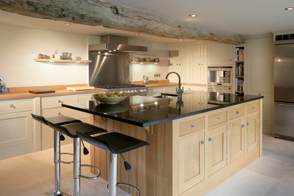 Foto di una cucina di medie dimensioni con ante con riquadro incassato, paraspruzzi a effetto metallico, paraspruzzi con piastrelle di metallo, elettrodomestici in acciaio inossidabile, pavimento beige e top nero