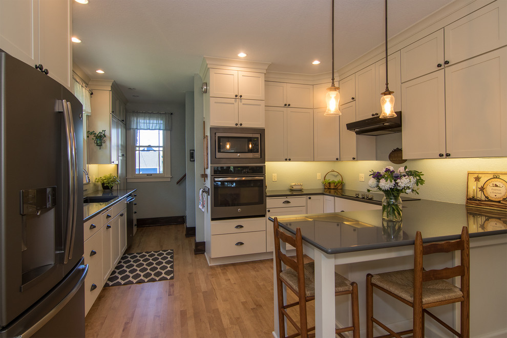 Small elegant u-shaped light wood floor and brown floor eat-in kitchen photo in Milwaukee with an undermount sink, shaker cabinets, white cabinets, quartzite countertops, a peninsula, gray countertops and stainless steel appliances