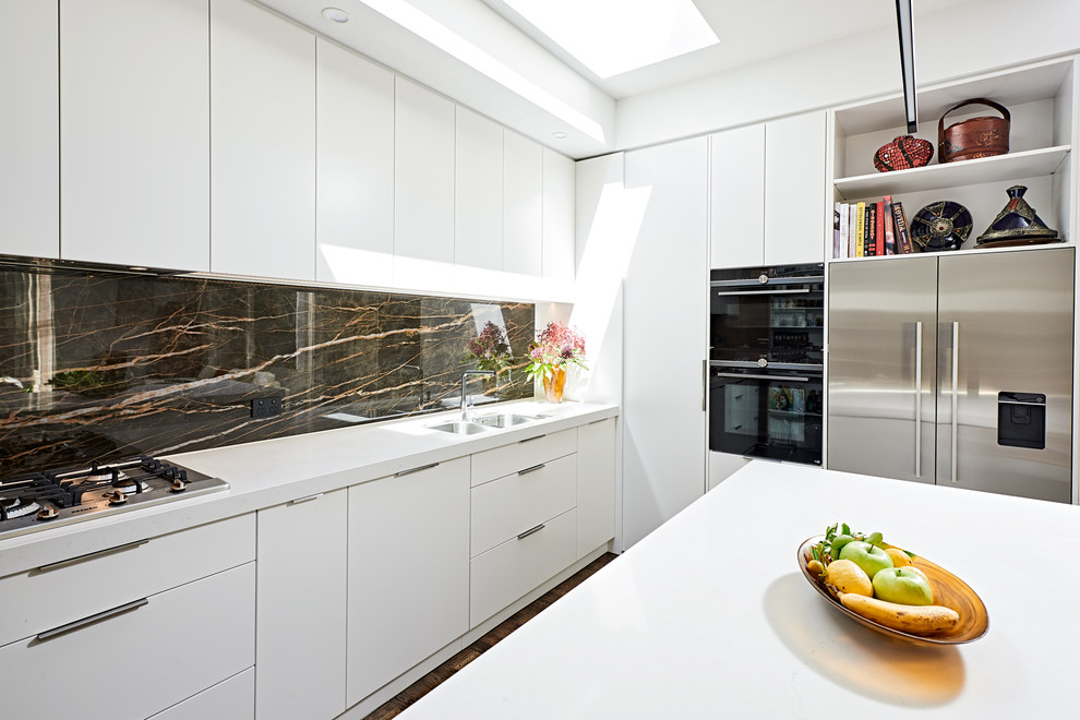 Esempio di una cucina moderna di medie dimensioni con lavello sottopiano, ante bianche, paraspruzzi nero, paraspruzzi in lastra di pietra, elettrodomestici in acciaio inossidabile, pavimento in legno massello medio, pavimento marrone e top bianco