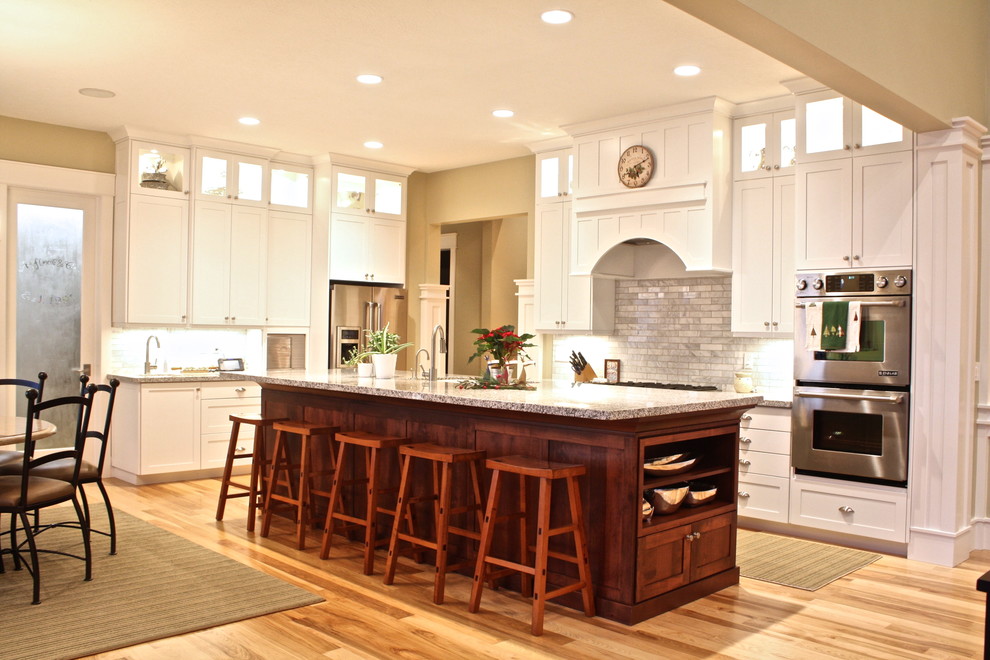 Exemple d'une cuisine chic avec un placard à porte shaker, des portes de placard blanches, une crédence blanche, une crédence en carrelage de pierre et un électroménager en acier inoxydable.