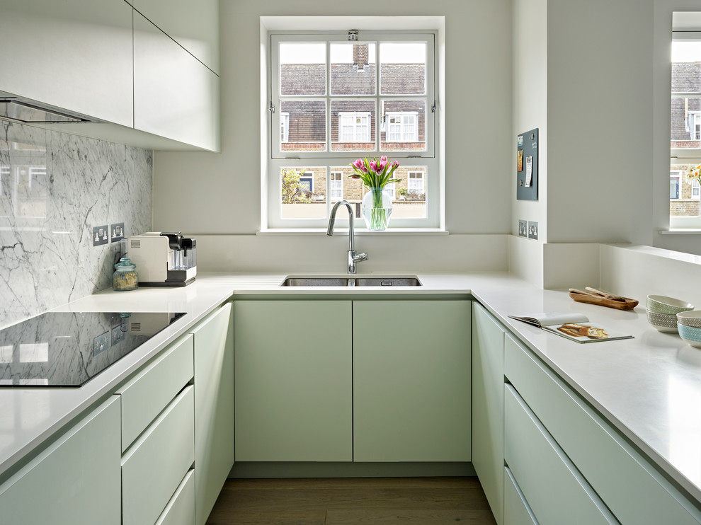 Inredning av ett modernt litet vit vitt u-kök, med en dubbel diskho, släta luckor, gröna skåp, flerfärgad stänkskydd, stänkskydd i marmor, ljust trägolv och beiget golv