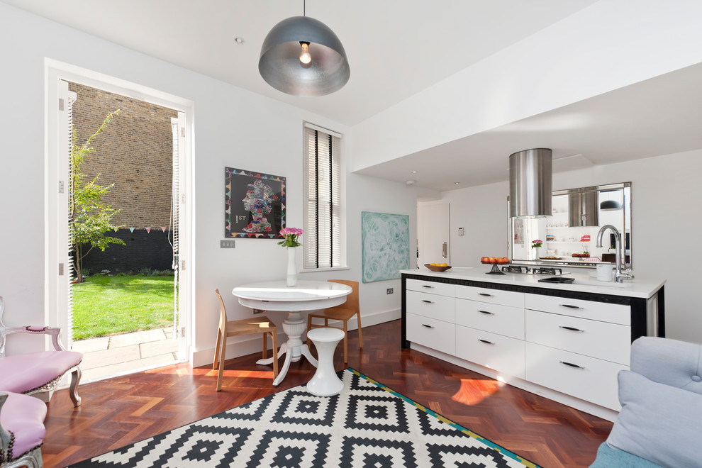 Kleine Moderne Küche mit weißen Schränken, Mineralwerkstoff-Arbeitsplatte, Küchengeräten aus Edelstahl, dunklem Holzboden, Kücheninsel, rotem Boden und weißer Arbeitsplatte in London