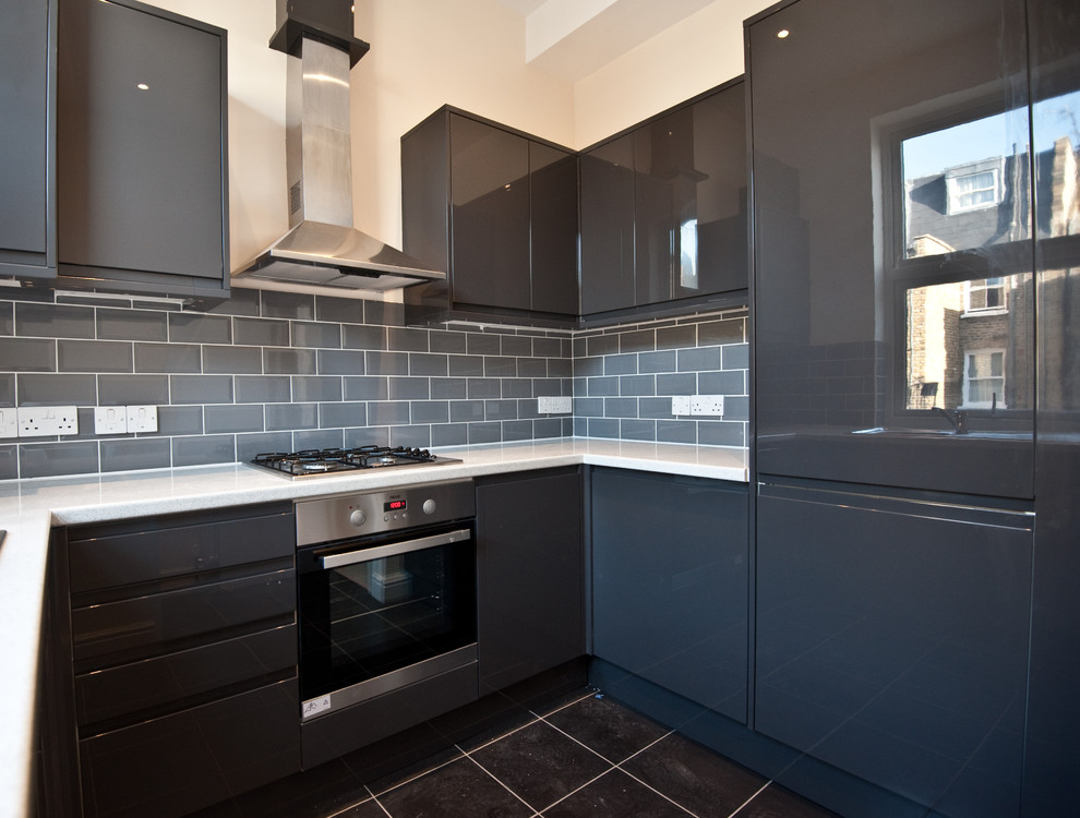 Large modern u-shaped enclosed kitchen in London with a built-in sink, flat-panel cabinets, black cabinets, engineered stone countertops, grey splashback, ceramic splashback, stainless steel appliances, ceramic flooring and no island.