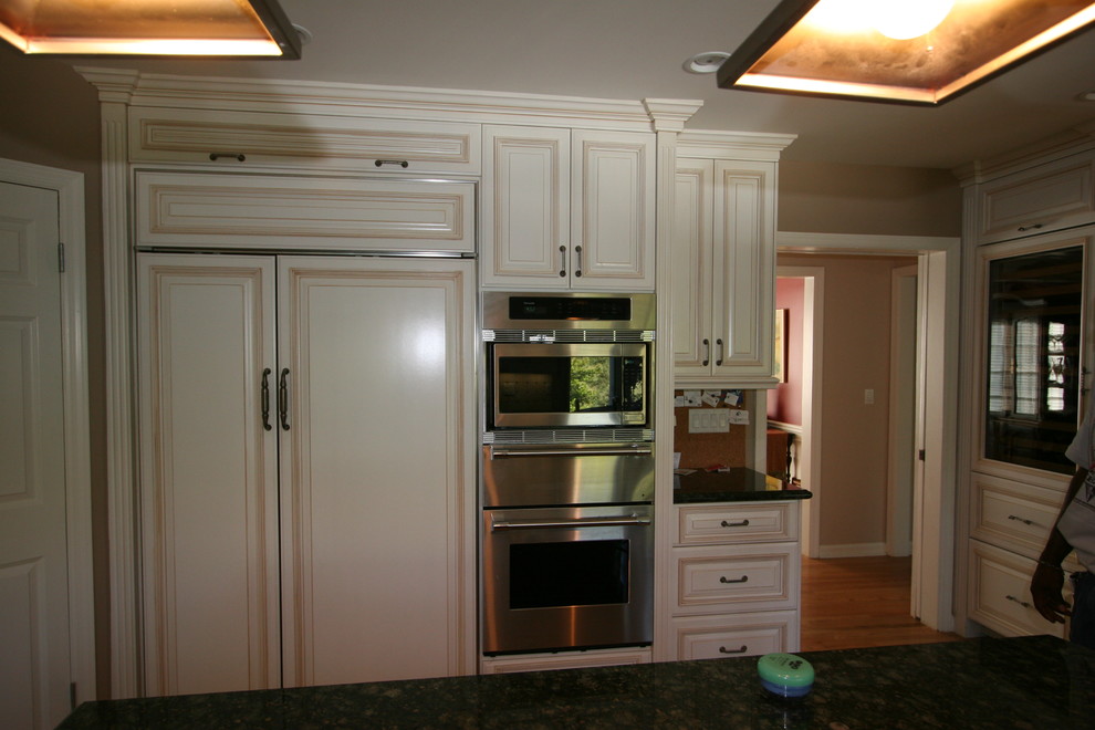 Bild på ett stort vintage kök med öppen planlösning, med vita skåp, granitbänkskiva, vitt stänkskydd, stänkskydd i keramik, rostfria vitvaror, mellanmörkt trägolv och en köksö