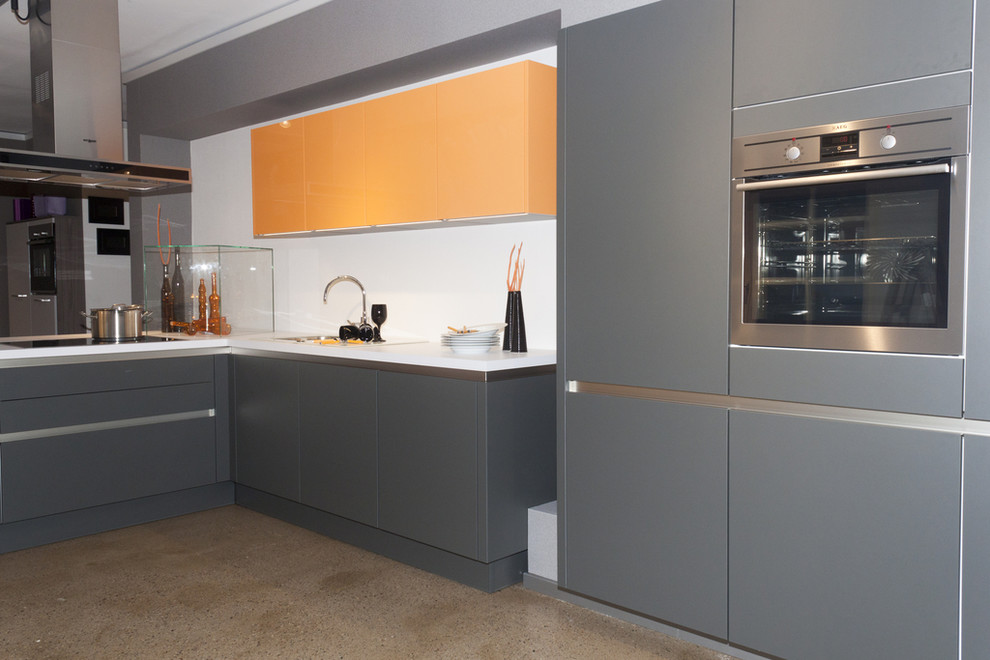 Modelo de cocina minimalista de tamaño medio con armarios con paneles lisos, puertas de armario naranjas y encimera de cuarzo compacto