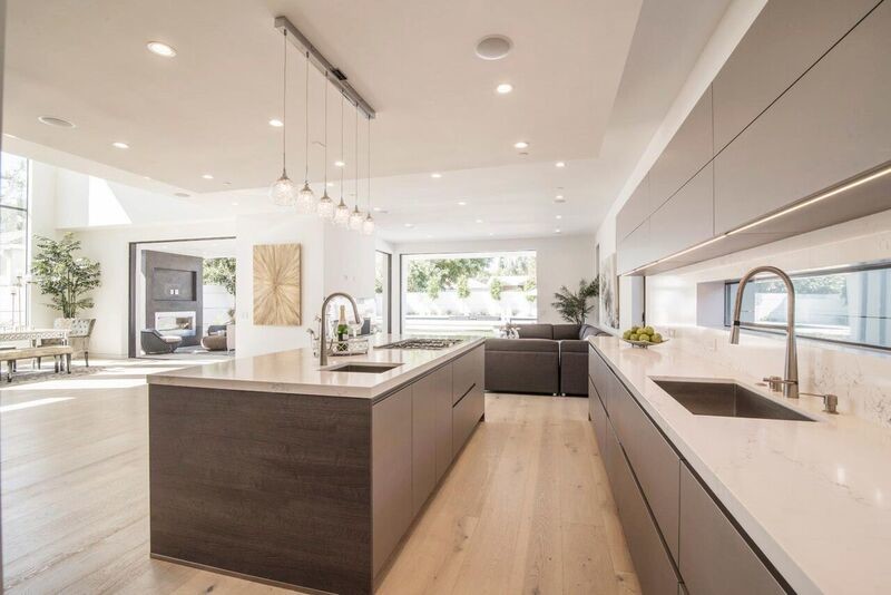 Idéer för ett stort modernt vit linjärt kök med öppen planlösning, med en undermonterad diskho, släta luckor, grå skåp, bänkskiva i kvartsit, vitt stänkskydd, stänkskydd i sten, mellanmörkt trägolv, en köksö och brunt golv