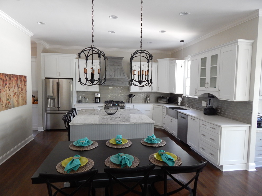 Inspiration for a large timeless l-shaped dark wood floor eat-in kitchen remodel in Charlotte with a farmhouse sink, shaker cabinets, white cabinets, granite countertops, gray backsplash, glass tile backsplash, stainless steel appliances and an island