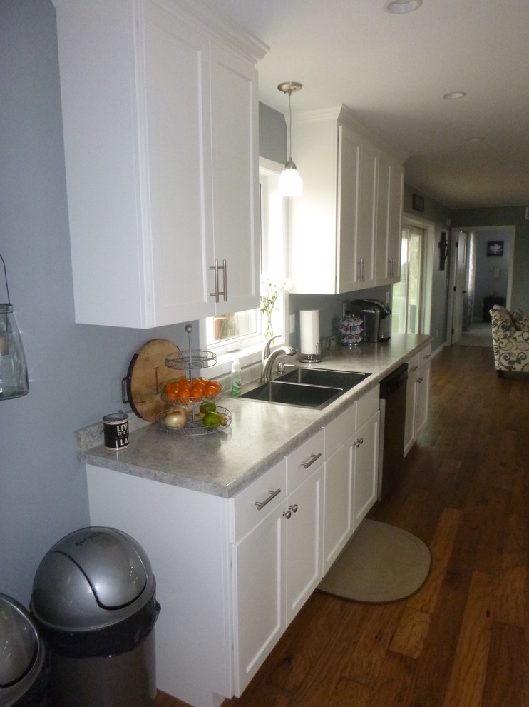 Klassisk inredning av ett mellanstort kök, med en dubbel diskho, skåp i shakerstil, vita skåp, laminatbänkskiva, blått stänkskydd, mellanmörkt trägolv, en köksö och brunt golv
