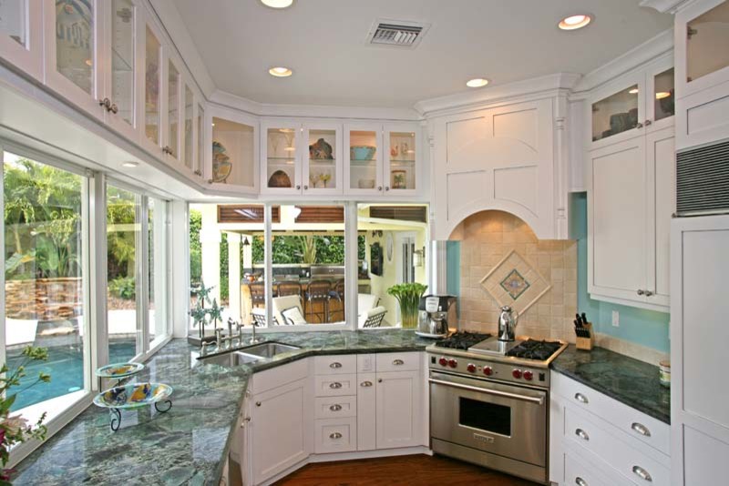 Exempel på ett exotiskt kök och matrum, med luckor med glaspanel, vita skåp, granitbänkskiva, rostfria vitvaror och mellanmörkt trägolv