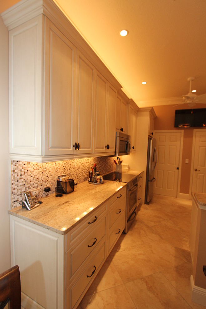 Inredning av ett klassiskt mellanstort kök, med en undermonterad diskho, luckor med upphöjd panel, granitbänkskiva, flerfärgad stänkskydd, rostfria vitvaror, klinkergolv i porslin, vita skåp, stänkskydd i mosaik och en halv köksö