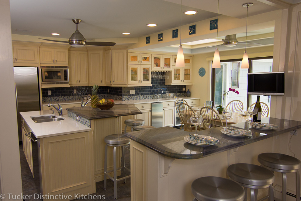 Immagine di un cucina con isola centrale stile marino con ante a filo, ante gialle, top in quarzite, paraspruzzi con piastrelle di vetro e elettrodomestici in acciaio inossidabile