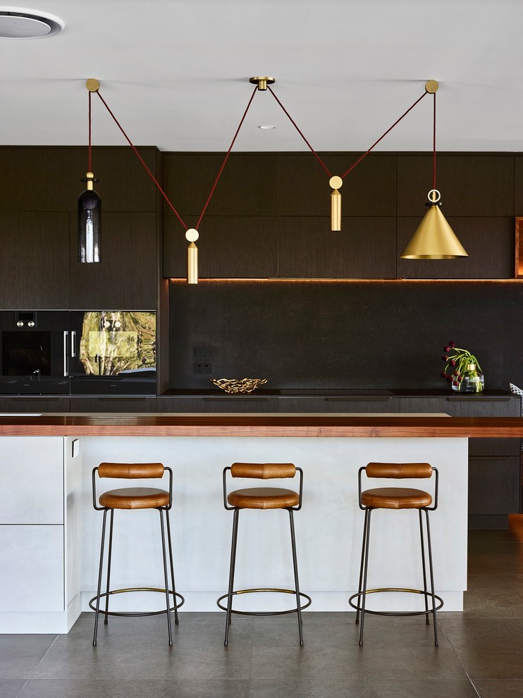 This is an example of a large contemporary galley kitchen in Brisbane with flat-panel cabinets, dark wood cabinets, black splashback, black appliances, an island, black worktops and grey floors.
