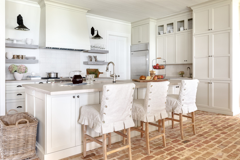 Exempel på ett shabby chic-inspirerat kök, med skåp i shakerstil, vita skåp, vitt stänkskydd, rostfria vitvaror, tegelgolv, en köksö, rött golv och bänkskiva i betong