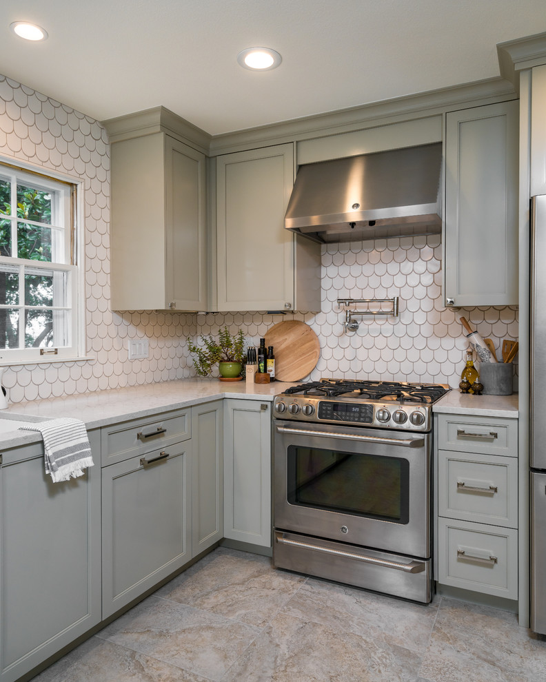 Classic l-shaped enclosed kitchen in Other with shaker cabinets, grey cabinets, engineered stone countertops, white splashback, ceramic splashback, stainless steel appliances, porcelain flooring and grey floors.