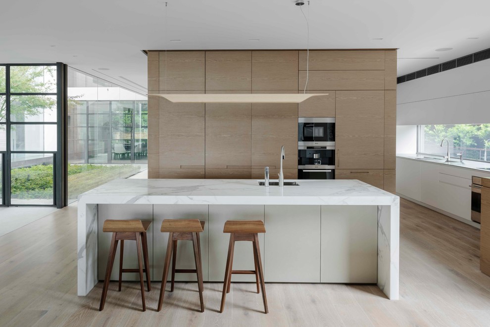 Esempio di una cucina minimalista con lavello sottopiano, ante di vetro, ante in legno chiaro, paraspruzzi a finestra, elettrodomestici da incasso, parquet chiaro, pavimento beige e top bianco