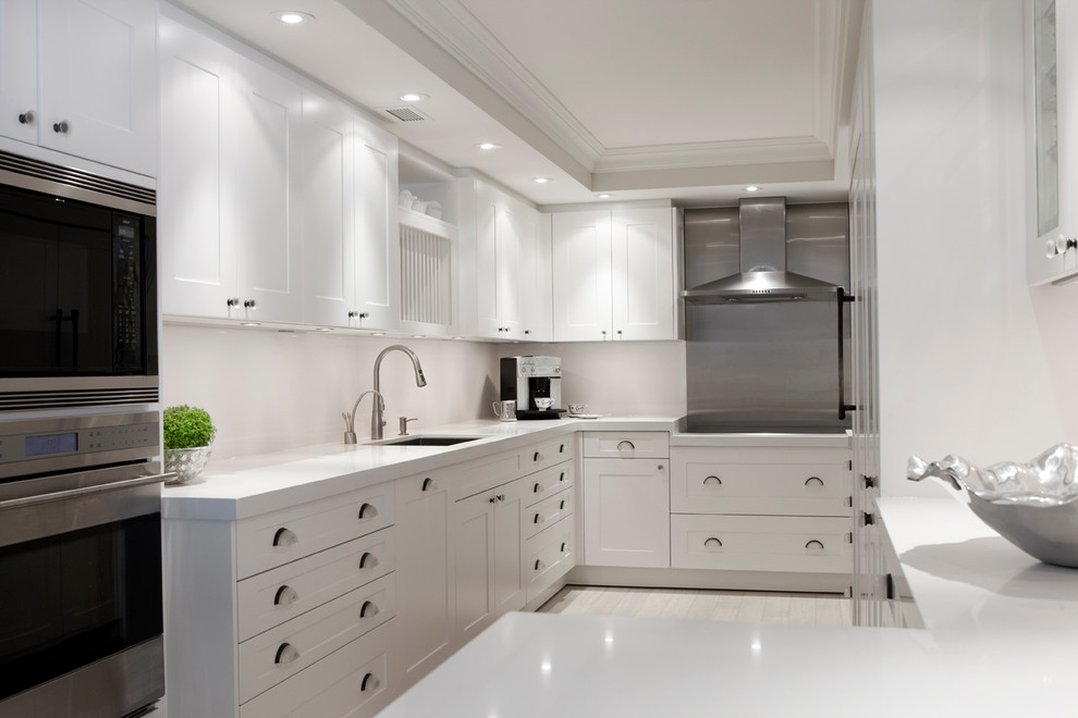 Example of a trendy u-shaped tray ceiling and gray floor kitchen pantry design in Toronto with an undermount sink, shaker cabinets, white cabinets, quartz countertops, white backsplash, stainless steel appliances, no island and white countertops
