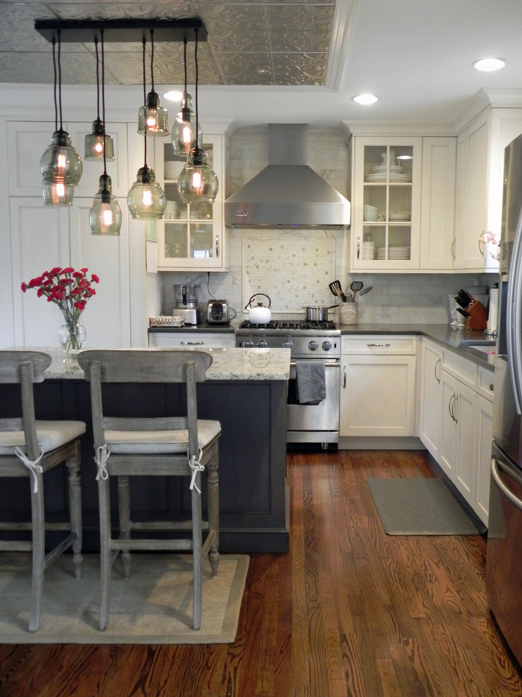 Enclosed kitchen - mid-sized traditional l-shaped medium tone wood floor enclosed kitchen idea in Baltimore with a triple-bowl sink, shaker cabinets, white cabinets, granite countertops, white backsplash, mosaic tile backsplash, stainless steel appliances and an island