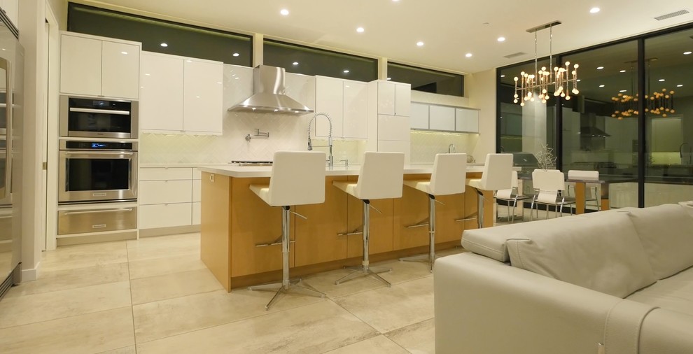 サンディエゴにあるラグジュアリーな広いコンテンポラリースタイルのおしゃれなキッチン (ドロップインシンク、フラットパネル扉のキャビネット、白いキャビネット、ラミネートカウンター、白いキッチンパネル、サブウェイタイルのキッチンパネル、シルバーの調理設備、トラバーチンの床、ベージュの床) の写真