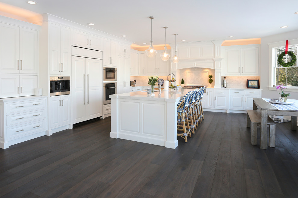 Design ideas for an expansive traditional l-shaped kitchen/diner in Boston with white cabinets, white splashback, dark hardwood flooring, an island and grey floors.