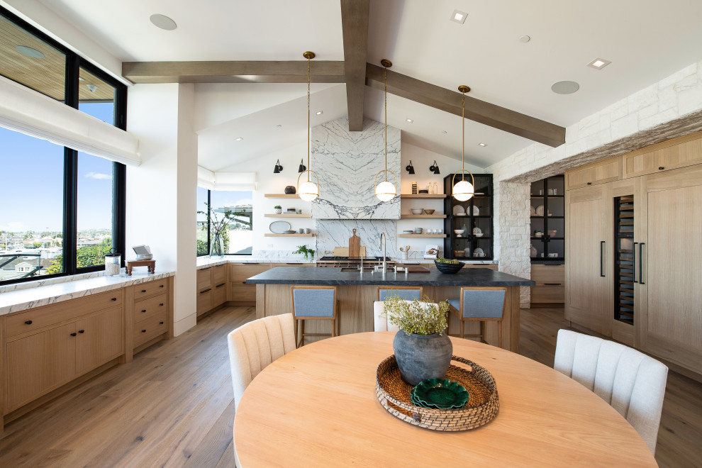 Photo of a medium sized traditional u-shaped kitchen/diner in Orange County with a submerged sink, recessed-panel cabinets, light wood cabinets, marble worktops, white splashback, stone slab splashback, integrated appliances, light hardwood flooring, an island, beige floors and white worktops.