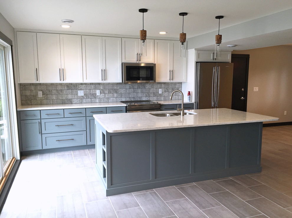 This is an example of a medium sized country u-shaped kitchen in Minneapolis with a submerged sink, recessed-panel cabinets, blue cabinets, multi-coloured splashback, stainless steel appliances, an island and grey floors.