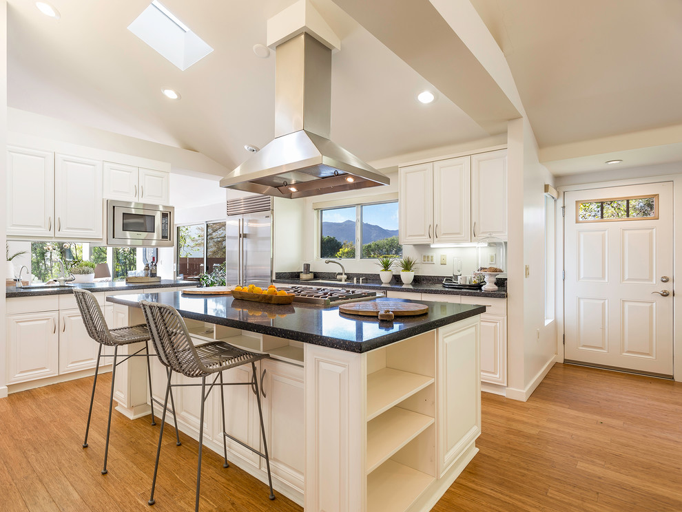 Medium sized retro enclosed kitchen in Los Angeles with a submerged sink, raised-panel cabinets, white cabinets, granite worktops, stainless steel appliances, light hardwood flooring and an island.