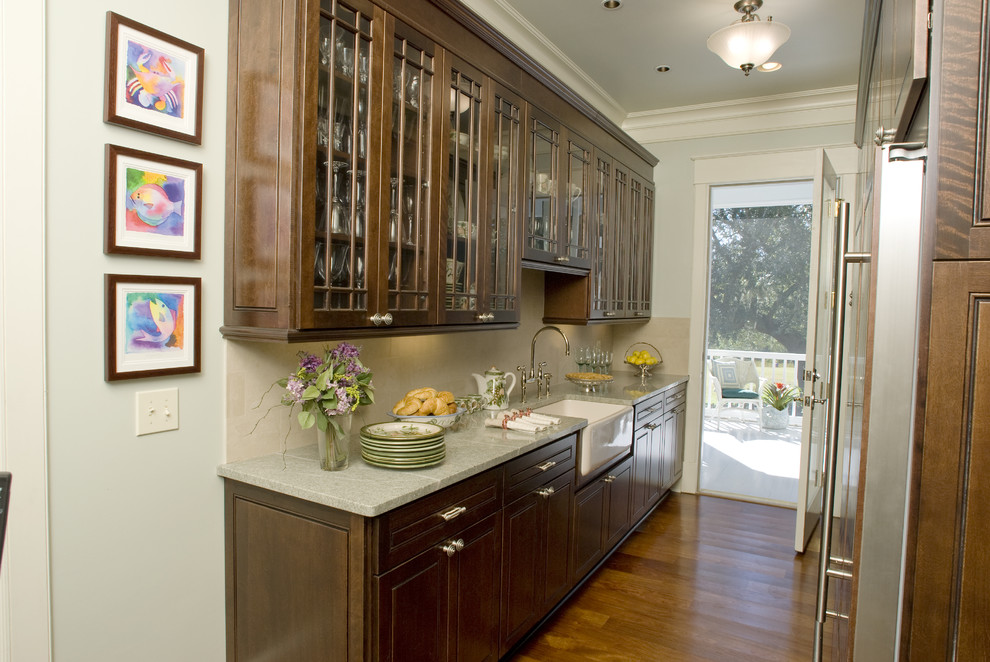 Medium sized traditional single-wall kitchen pantry in New Orleans with a belfast sink, glass-front cabinets, dark wood cabinets, medium hardwood flooring and no island.