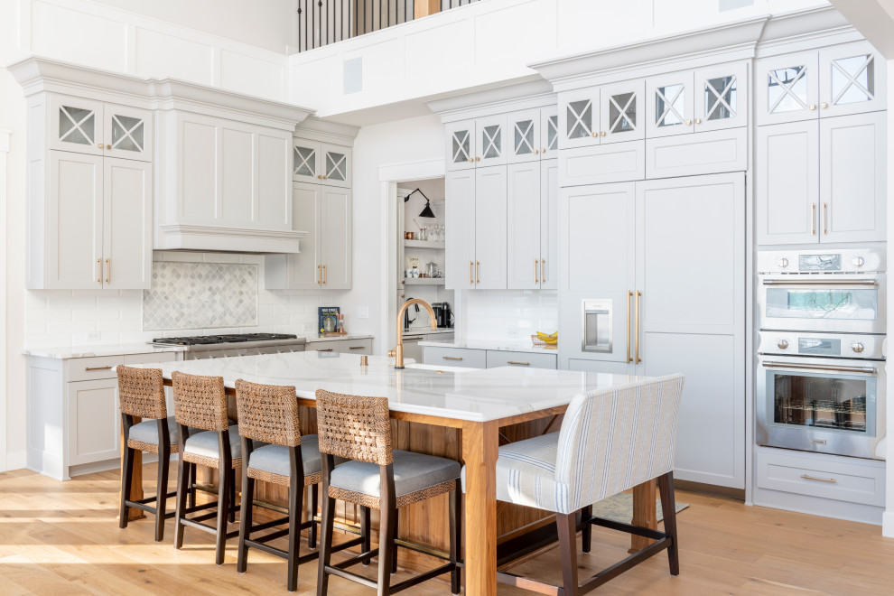 Klassisk inredning av ett flerfärgad flerfärgat kök, med en rustik diskho, skåp i shakerstil, grå skåp, vitt stänkskydd, stänkskydd i tunnelbanekakel, integrerade vitvaror, mellanmörkt trägolv, en köksö och brunt golv