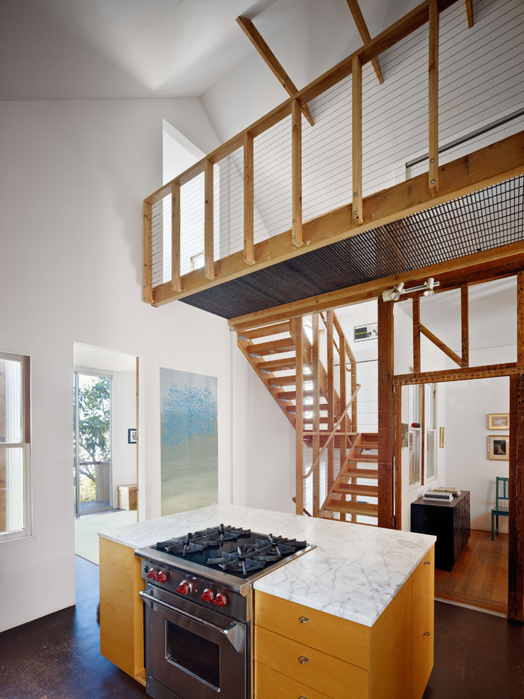 Bild på ett funkis kök, med släta luckor, rostfria vitvaror, marmorbänkskiva och skåp i mellenmörkt trä