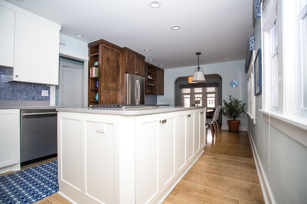 Mid-sized trendy single-wall light wood floor eat-in kitchen photo in New York with an undermount sink, shaker cabinets, dark wood cabinets, quartz countertops, blue backsplash, subway tile backsplash, stainless steel appliances and an island