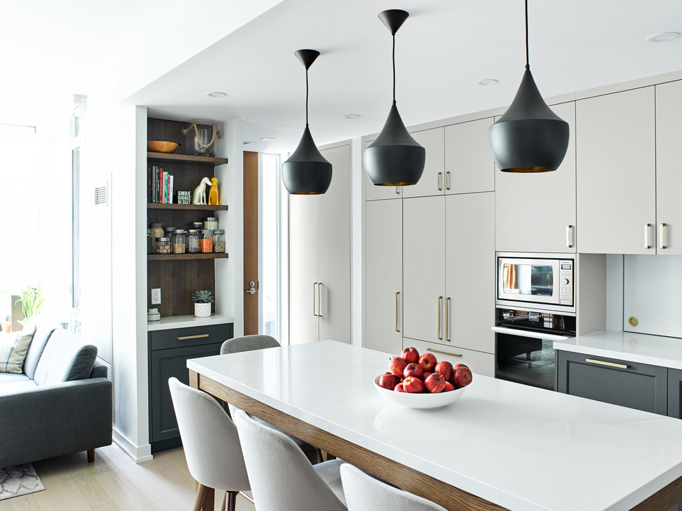 Immagine di una cucina minimal con ante lisce, ante grigie, paraspruzzi bianco, elettrodomestici neri, parquet chiaro, pavimento marrone e top bianco