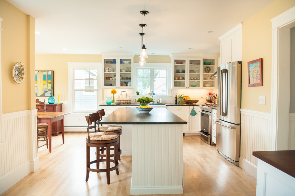 Traditional kitchen in Portland Maine with glass-front cabinets, white splashback, metro tiled splashback and stainless steel appliances.