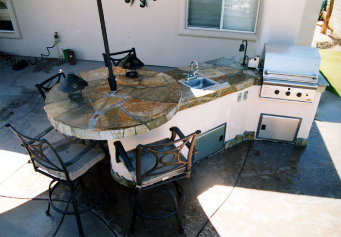 Exempel på ett klassiskt linjärt kök, med en enkel diskho, släta luckor, skåp i rostfritt stål, rostfria vitvaror och betonggolv