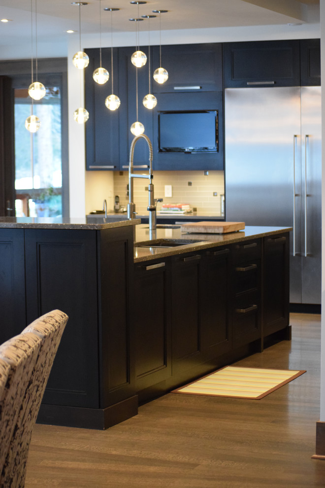 Immagine di un cucina con isola centrale minimalista con ante lisce, ante in legno bruno, elettrodomestici in acciaio inossidabile e pavimento in legno massello medio
