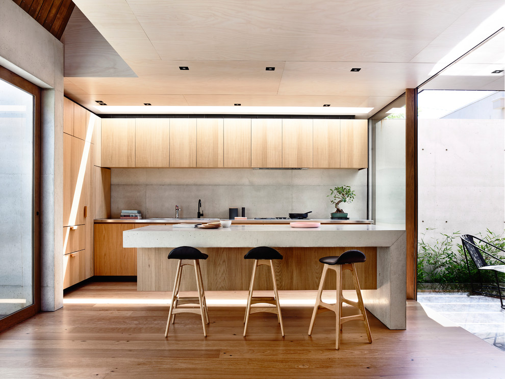 Zweizeilige, Kleine Moderne Küche mit Betonarbeitsplatte, Küchenrückwand in Grau, braunem Holzboden, Kücheninsel und hellen Holzschränken in Melbourne