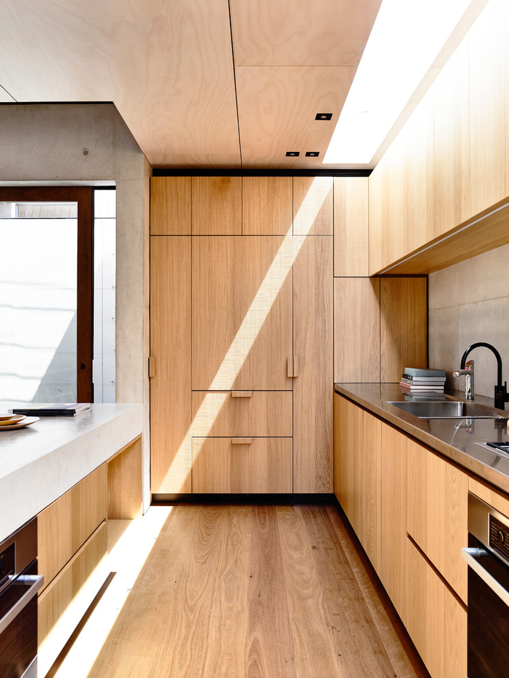 Exemple d'une petite cuisine parallèle moderne en bois brun avec un évier 2 bacs, un plan de travail en béton, une crédence grise, un sol en bois brun, îlot et un électroménager en acier inoxydable.