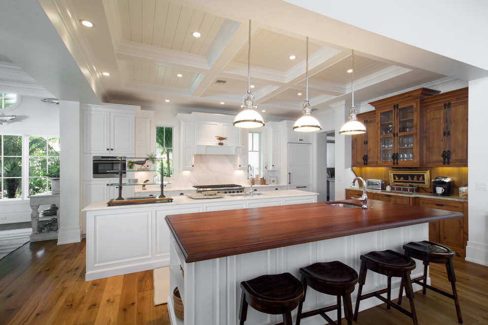 Eat-in kitchen - large traditional single-wall eat-in kitchen idea in Miami with raised-panel cabinets, white cabinets, white backsplash, paneled appliances and two islands