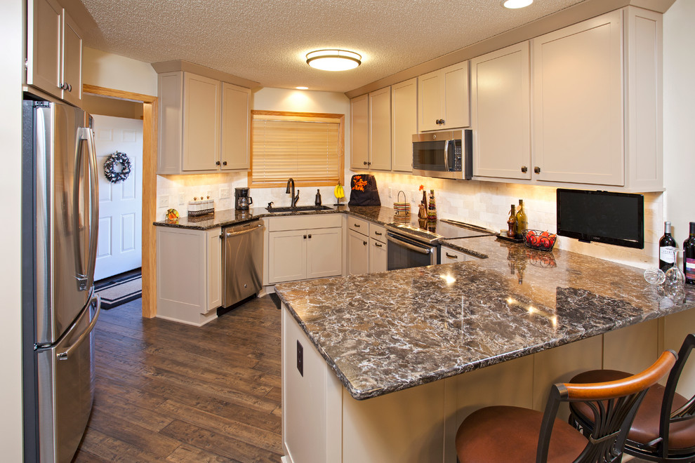 Exempel på ett avskilt, mellanstort klassiskt u-kök, med en undermonterad diskho, skåp i shakerstil, beige skåp, bänkskiva i kvarts, beige stänkskydd, stänkskydd i tunnelbanekakel, rostfria vitvaror, mellanmörkt trägolv och en halv köksö