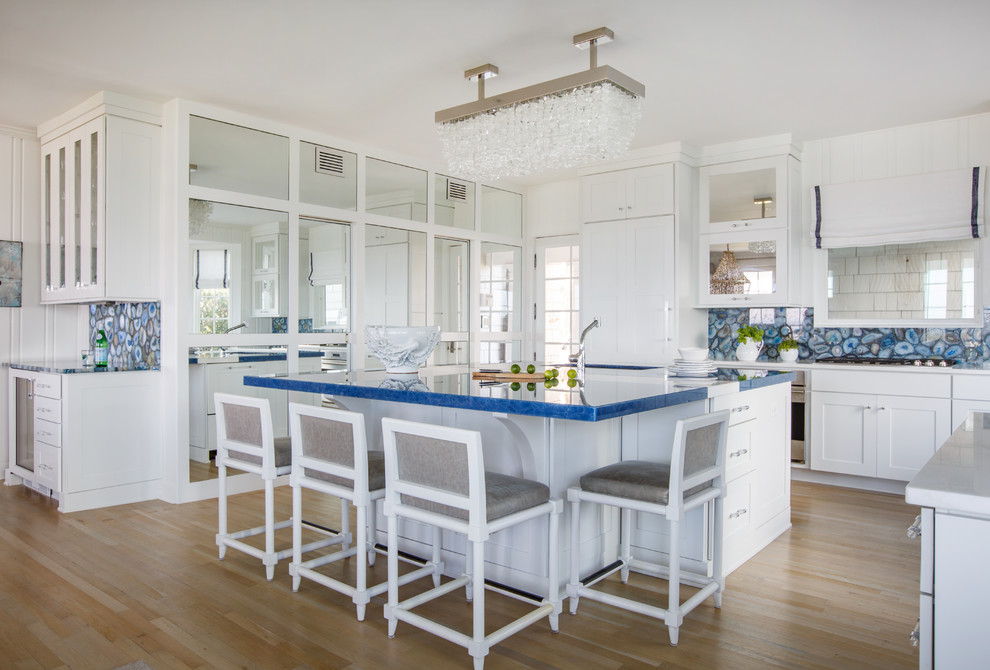 Réalisation d'une cuisine encastrable marine en U avec un placard à porte shaker, des portes de placard blanches, une crédence bleue, parquet clair, îlot, un sol beige et un plan de travail bleu.