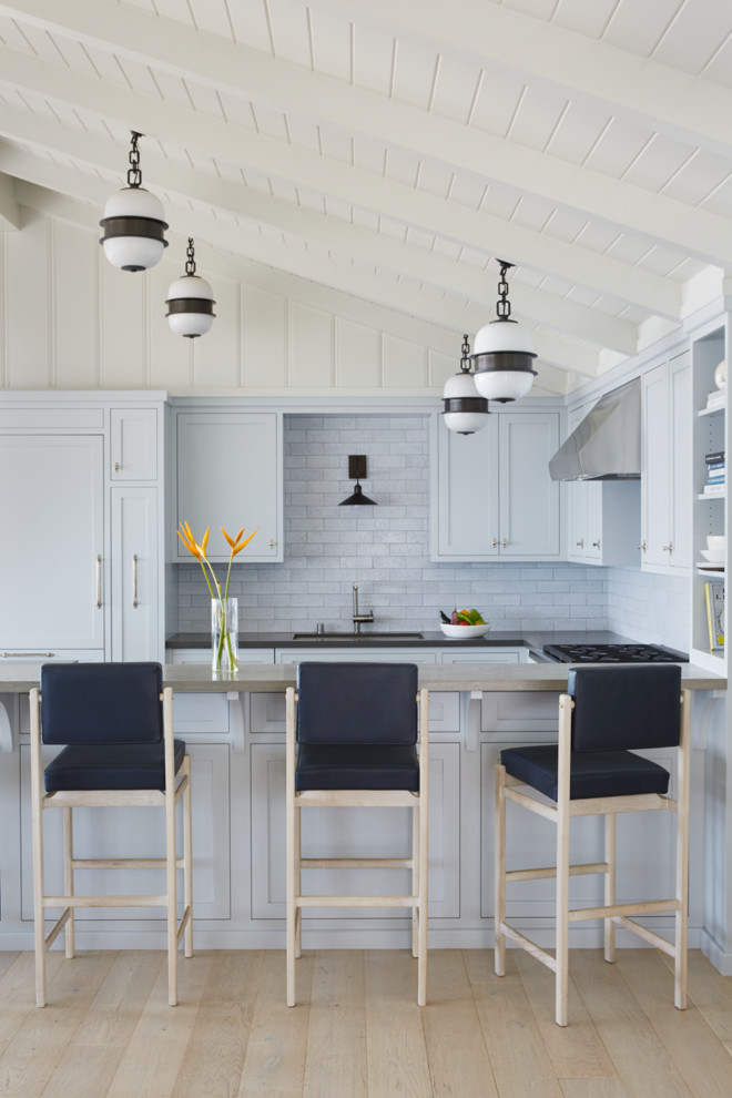 Immagine di una cucina stile marino con ante in stile shaker, ante bianche, paraspruzzi grigio, parquet chiaro, penisola, pavimento beige e top beige