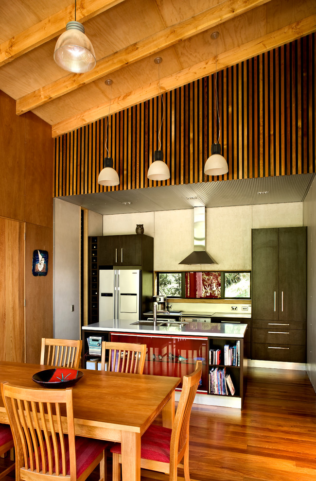 На фото: прямая кухня в стиле рустика с плоскими фасадами, темными деревянными фасадами, белой техникой, паркетным полом среднего тона и островом с