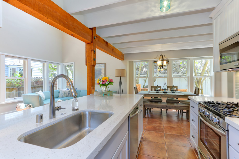 Mid-sized beach style galley terra-cotta tile and brown floor open concept kitchen photo in Other with a single-bowl sink, beaded inset cabinets, quartz countertops, blue backsplash, glass tile backsplash, stainless steel appliances, white cabinets and a peninsula