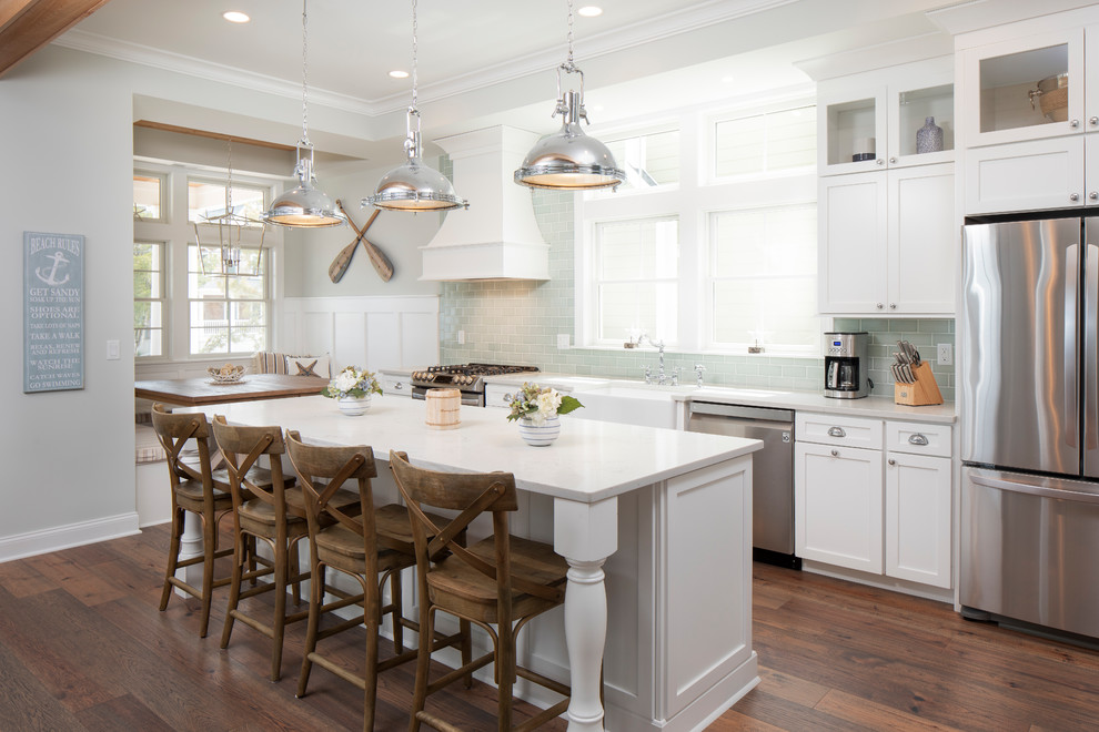 Inspiration for a mid-sized coastal galley dark wood floor and brown floor kitchen remodel in New York with a farmhouse sink, shaker cabinets, white cabinets, quartzite countertops, green backsplash, glass tile backsplash, stainless steel appliances, an island and white countertops