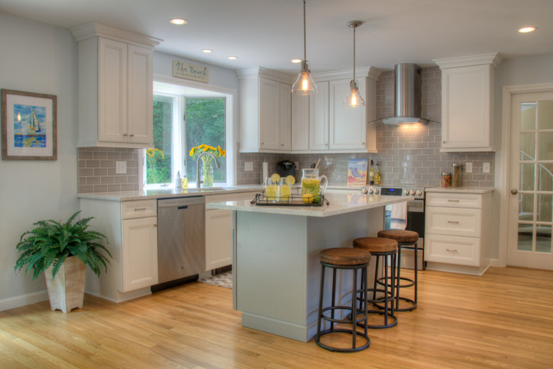 Inspiration for a large transitional u-shaped medium tone wood floor eat-in kitchen remodel in Providence with an undermount sink, recessed-panel cabinets, white cabinets, quartz countertops, gray backsplash, glass tile backsplash, stainless steel appliances and an island