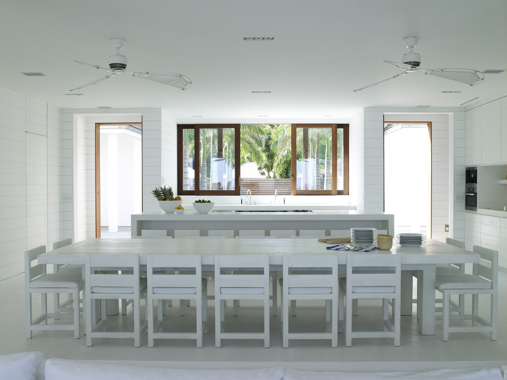 Expansive scandi l-shaped kitchen/diner in London with beaded cabinets, white cabinets, white splashback, quartz worktops, concrete flooring and white floors.