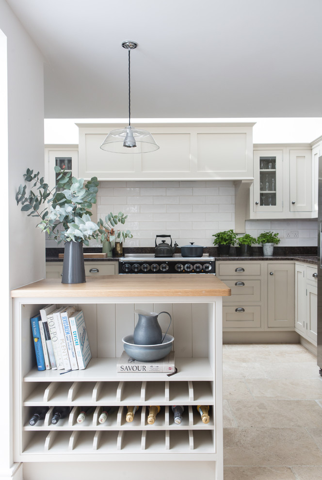 Beach style travertine floor kitchen photo in London with shaker cabinets, white cabinets, white backsplash, subway tile backsplash and a peninsula