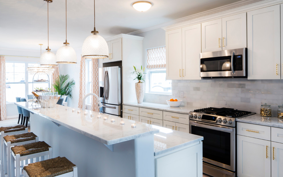 Example of a large beach style single-wall eat-in kitchen design in Miami with shaker cabinets, white cabinets, quartzite countertops, gray backsplash, marble backsplash, stainless steel appliances and an island