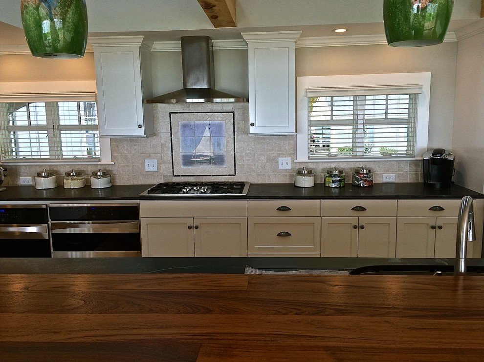 Photo of a small beach style galley kitchen pantry in Boston with a submerged sink, flat-panel cabinets, white cabinets, soapstone worktops, beige splashback, ceramic splashback, stainless steel appliances, light hardwood flooring and an island.